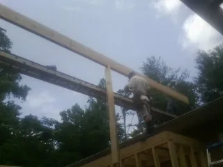 Carpenter setting a ridge beam over a new addition frame — Ice Dam Removal by Roofing Brothers in Flournoy