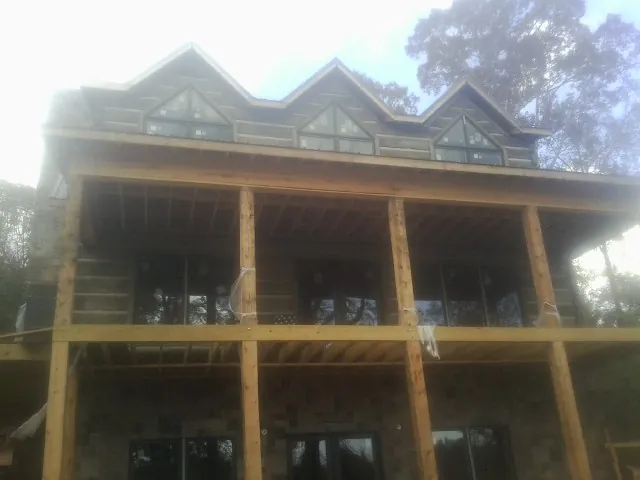 Dormers and porch framing on a large log home under construction — Roof Coating work by our crew in Flournoy