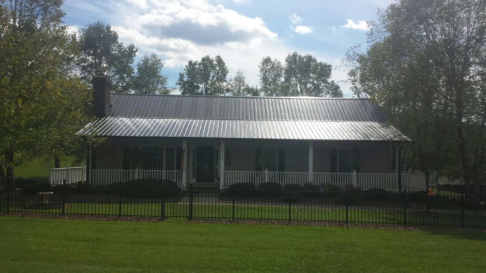 Gray metal roof on a brick ranch with a full width front porch — Gutter Guard Installation work by our crew in Flournoy