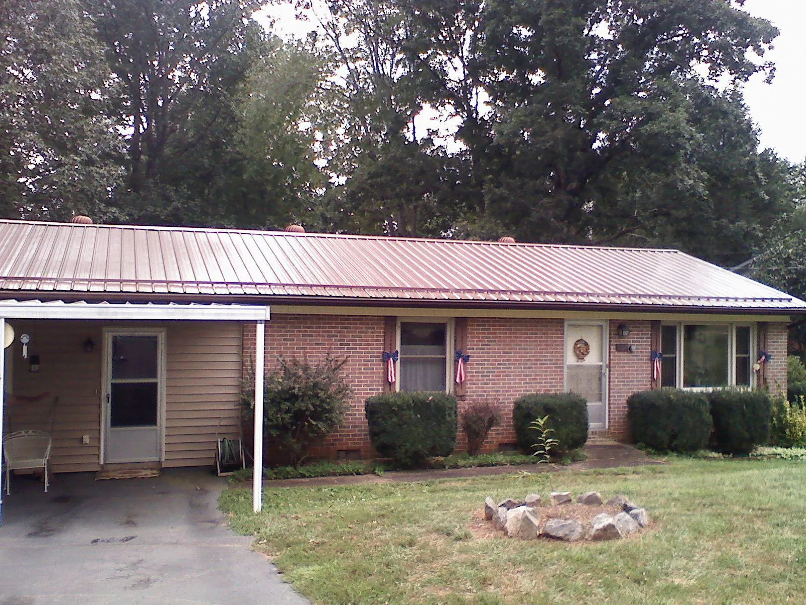Bronze metal roof and carport on a brick ranch home — Roof Repair work by our crew in Flournoy