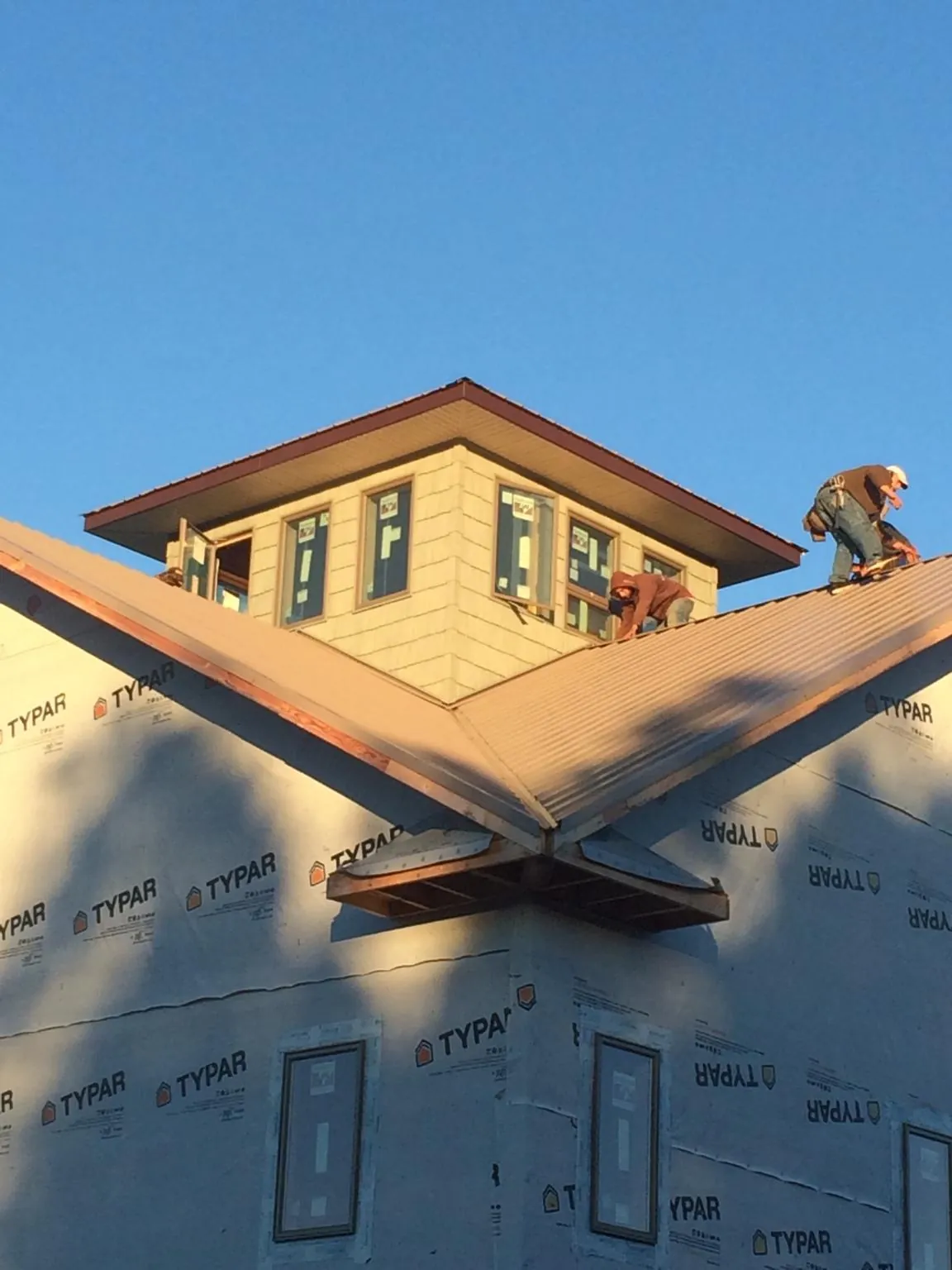 Roofers working around a rooftop cupola on a new metal roof at sunset — Roof Waterproofing in Flournoy by Roofing Brothers